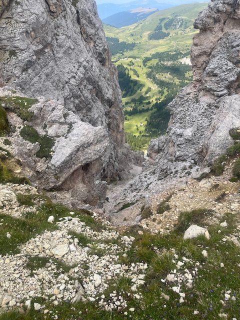 A rocky trail winding between limestone peaks, with a green valley far below